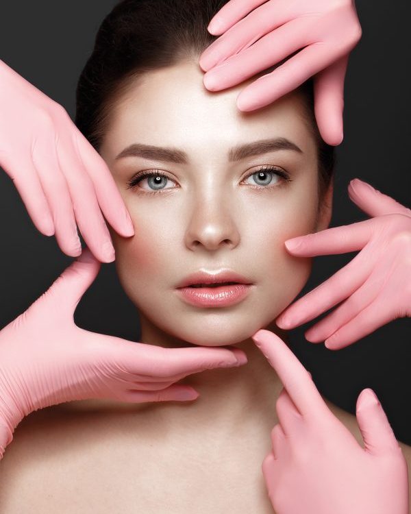 Beautiful young girl with natural nude make-up with cosmetic tools in hands. Beauty face. Photo taken in studio